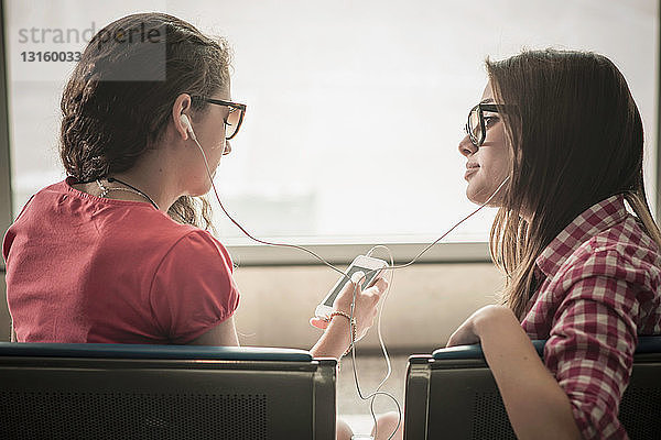 Zwei junge Mädchen mit Sonnenbrillen hören Musik