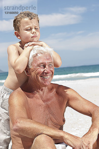 Älterer Mann mit Enkel am Strand