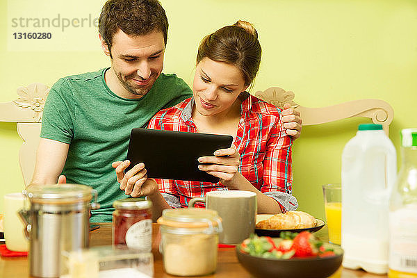 Junges Paar beim Frühstück  Frau mit digitalem Tablet