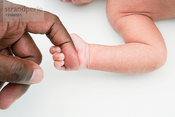 Junges Baby hält den Finger des Vaters