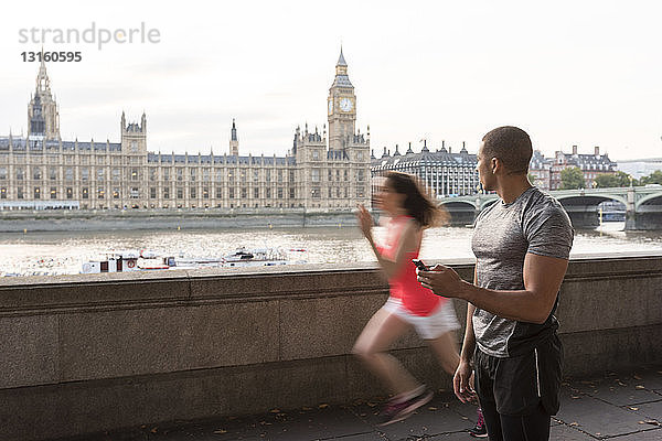 Männlicher Trainer bei der Zeitmessung einer Läuferin am Southbank  London  UK