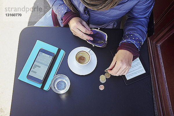 Hohe Winkel Ansicht der Mitte erwachsene Frau Zählen von Euro-Münzen auf dem Bürgersteig Cafe