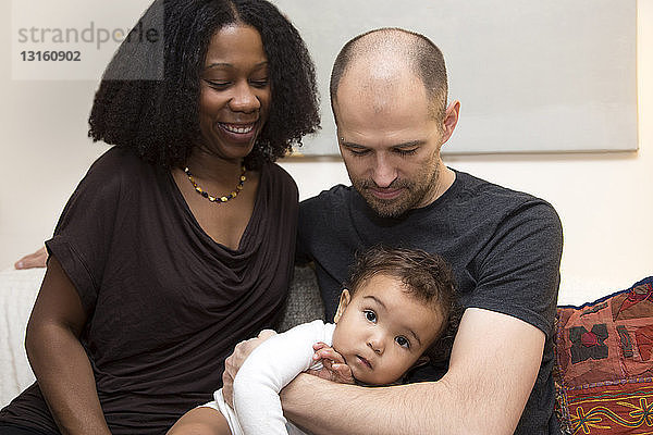 Porträt von Eltern mit Kleinkind und Tochter auf dem Sofa