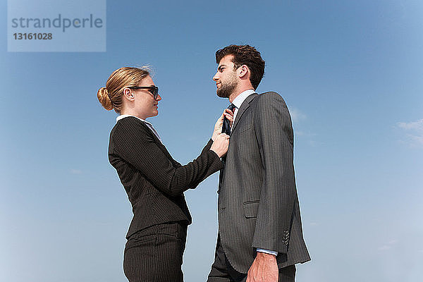 Geschäftsfrau richtet die Krawatte eines Kollegen