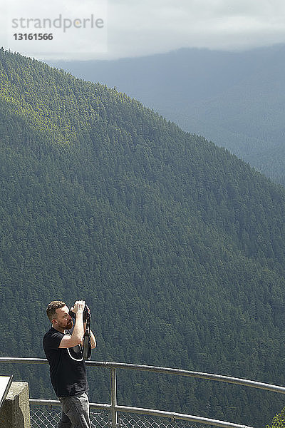 Männlicher Fotograf  der den Wald von einer Aussichtsplattform aus fotografiert  Olympische Berge  Bundesstaat Washington  USA