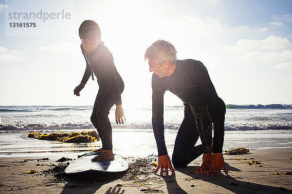 Vater und Sohn üben mit dem Surfbrett am Strand  Encinitas  Kalifornien  USA