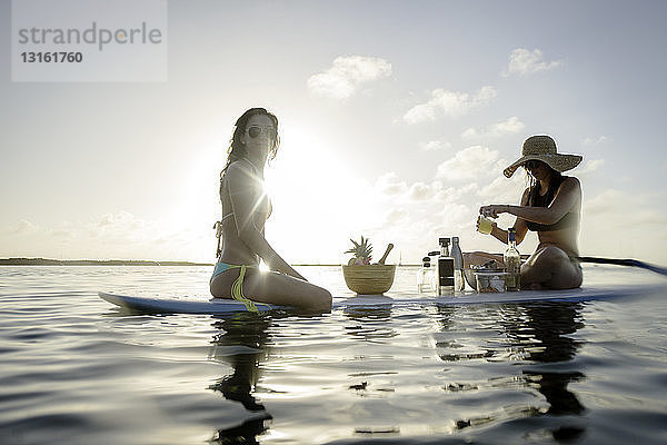 Zwei junge Frauen bereiten Cocktails auf dem Paddelbrett zu  Islamorada  Florida  USA