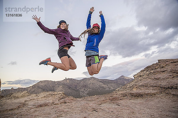 Zwei junge Bergsteigerinnen springen am Gipfel des Smith Rock  Oregon  USA  in die Luft