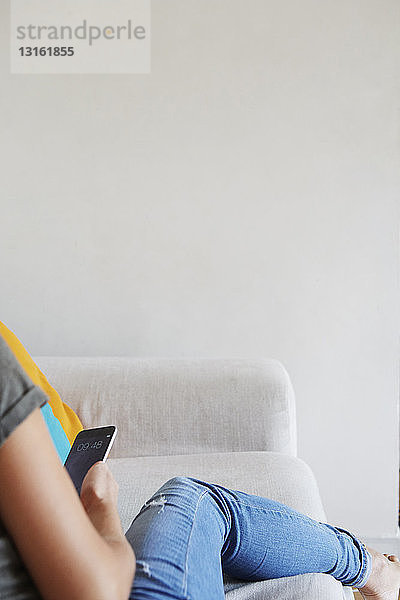 Frau benutzt Smartphone auf dem Sofa