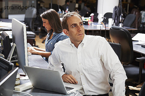 Mittelgroßer erwachsener Mann mit Laptop im Büro