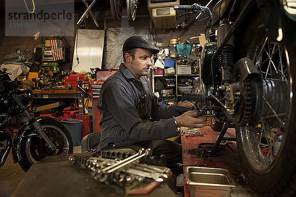 Mechaniker in seiner Garage beim Umbau von gasbetriebenen Motorrädern auf Bio-Diesel