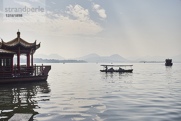 Blick auf die Silhouette eines Fischerbootes und eines Seerestaurants am Westlake  Hangzhou  China