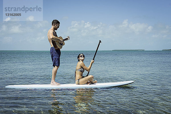 Junges Paar paddelnd und Gitarre spielend  Islamorada  Florida  USA