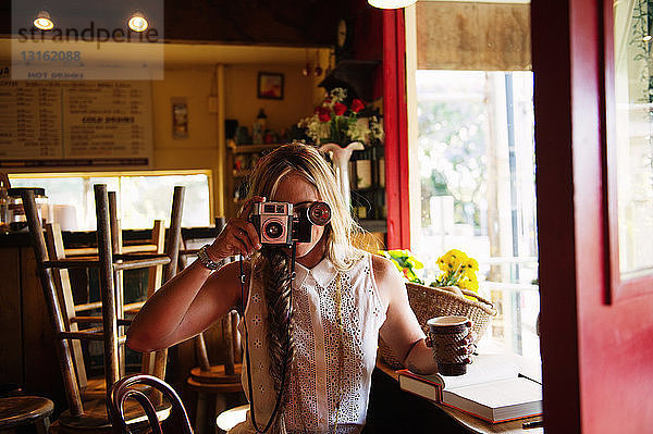 Junge Frau beim Fotografieren im Cafe