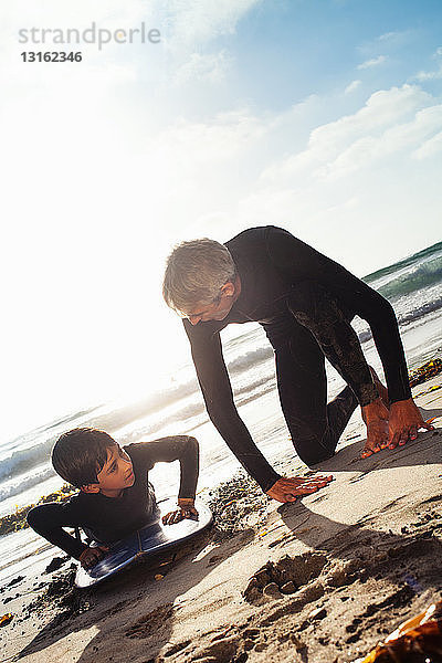 Vater und Sohn üben am Strand auf dem Surfbrett  Encinitas  Kalifornien  USA