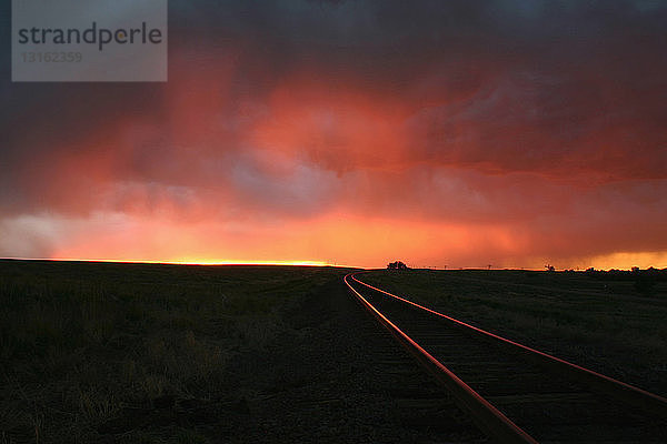 Intensive Farben des Sonnenuntergangs beleuchten die Eisenbahnschienen an diesem abgelegenen Ort  Burlington  Colorado  USA