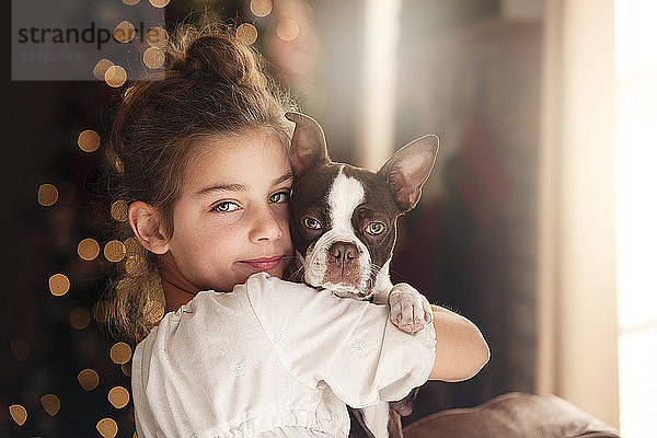 Porträt eines Mädchens und eines Boston Terriers vor dem Weihnachtsbaum