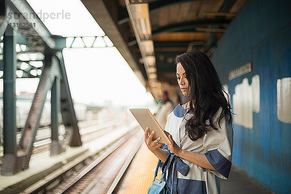 Mittelgroße erwachsene Frauen mit digitalem Tablet auf dem U-Bahn-Bahnsteig  Brooklyn  New York
