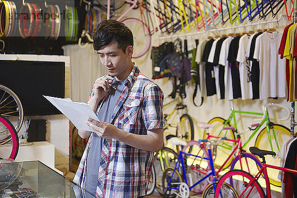 Junger Mann im Fahrradladen mit Papierkram