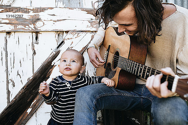 Vater unterhält Sohn mit Gitarre