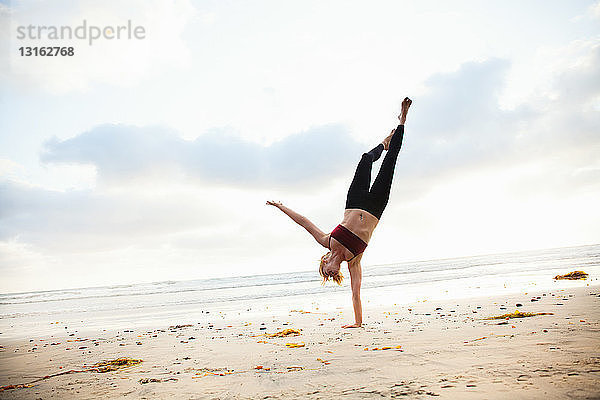 Mittlere erwachsene Frau  die Yogastellung am Strand praktiziert