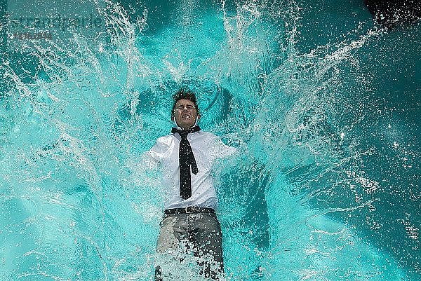 Junger Mann in Kleidung fällt in Schwimmbad