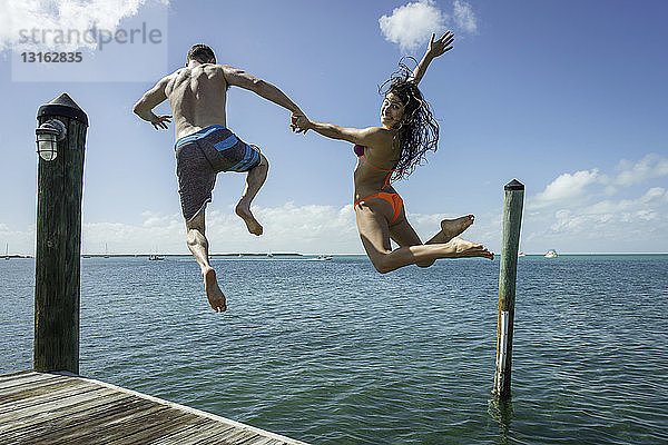 Rückansicht eines jungen Paares  das vom Seepier springt  Islamorada  Florida  USA