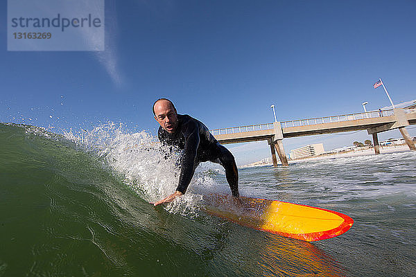 Mittelgroßer Erwachsener  der auf einem gelben Surfbrett neben der Brücke surft  Los Angeles  Kalifornien  USA