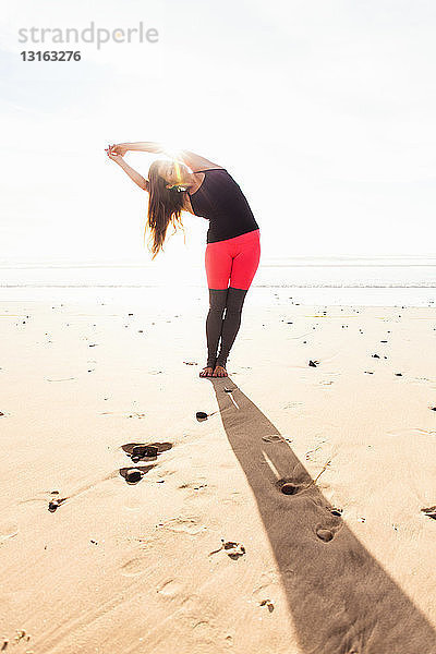 Frau in Yoga-Pose am Strand