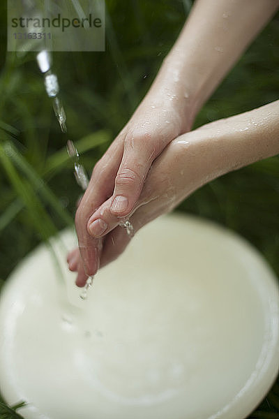 Junge Frau beim Händewaschen unter Blumenwasser  Nahaufnahme