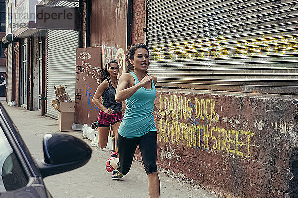 Zwei junge Läuferinnen laufen auf der Straße in der Stadt