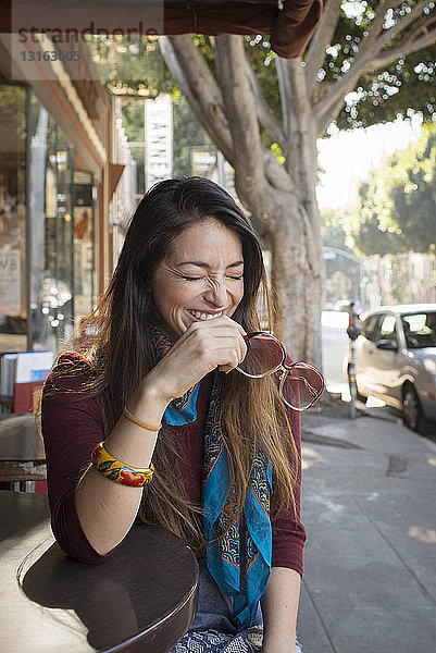 Junge Frau lacht im Bürgersteig-Café