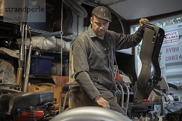 Mechaniker in seiner Garage beim Umbau von gasbetriebenen Motorrädern auf Bio-Diesel