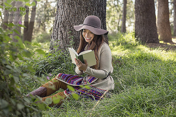 Junge Frau liest Buch im Wald