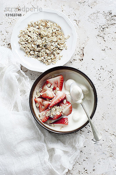 Stilleben von Joghurtschalen mit in Scheiben geschnittener Erdbeere und Hafer