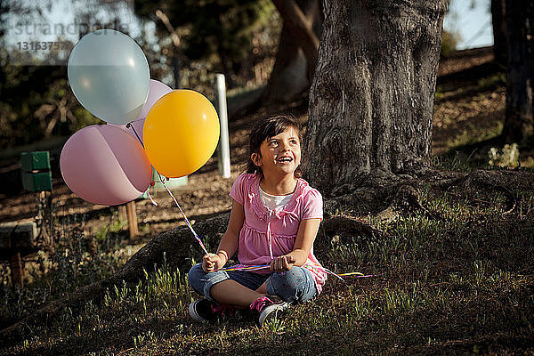 Mädchen auf Gras hält Luftballons