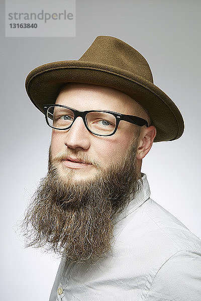 Studioporträt eines mittleren erwachsenen Mannes in Trilby mit übergroßem Bart