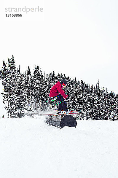 Seitenansicht eines Skifahrers beim Schleifen auf einem röhrenförmigen Hindernis  Whistler Terrain Park  British Columbia  Kanada