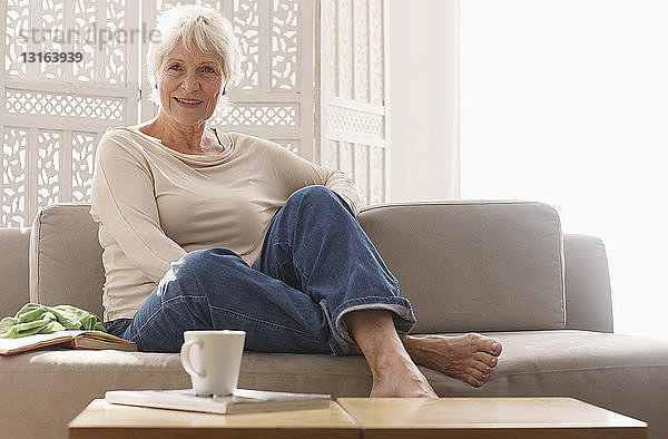 Ältere Frau entspannt sich zu Hause auf dem Sofa