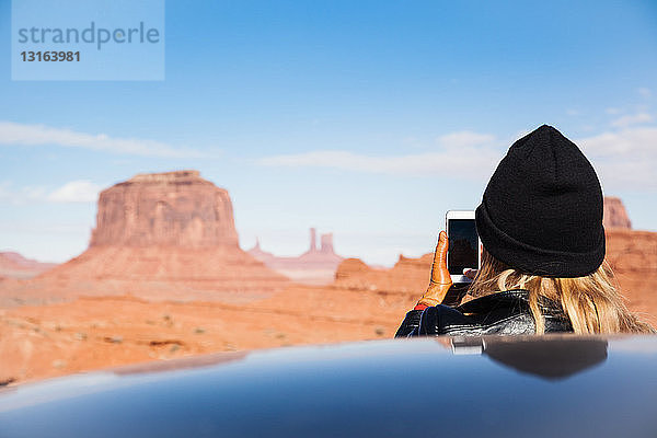 Rückansicht einer mittleren erwachsenen Frau  die Monument Valley auf einem Smartphone fotografiert  Utah  USA