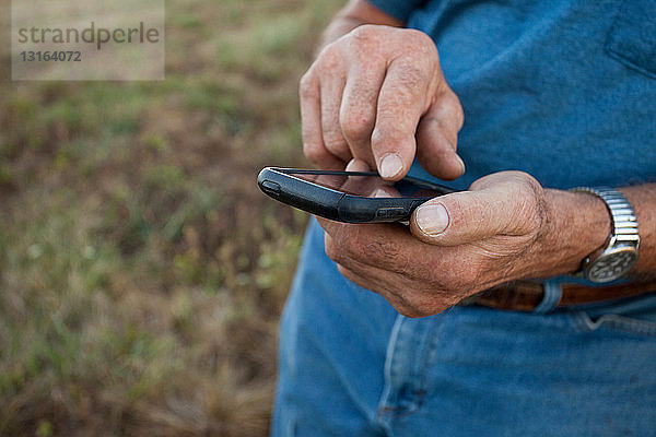 Nahaufnahme eines älteren Mannes beim Benutzen eines Mobiltelefons