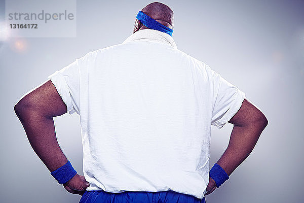 Erwachsener Mann trägt weißes T-Shirt mit Händen auf den Hüften  Rückenansicht