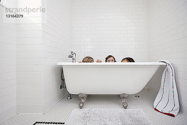 Drei junge Mädchen spähen über Bad