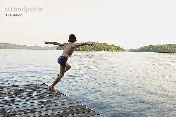 Junge springt vom Holzsteg in den See  Ontario  Kanada