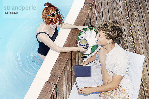 Draufsicht auf ein junges Paar  das sich am Pool unterhält