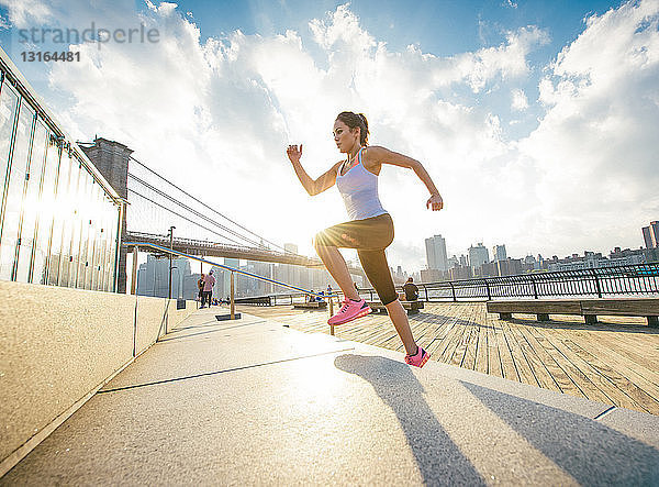 Läuferin läuft am Flussufer eine Treppe hinauf  New York  USA