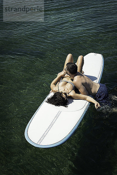 Draufsicht auf ein romantisches junges Paar auf einem Paddelbrett auf See