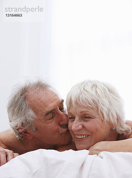 Älteres Paar küsst sich im Bett