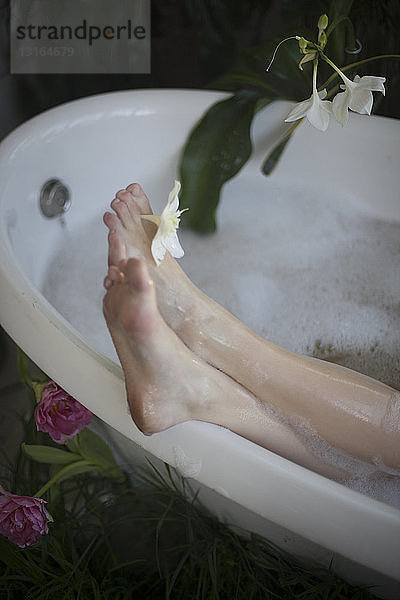 Junge Frau entspannt sich in der Badewanne  Füße auf dem Badewannenrand  Fokus auf die Füße