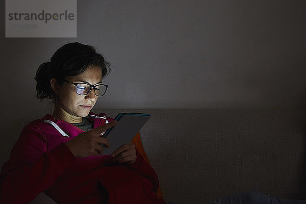 Frau benutzt digitales Tablett auf dem Sofa